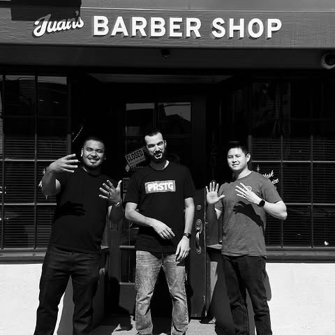 Three of the barbers outside the shop’s storefront, in black and white