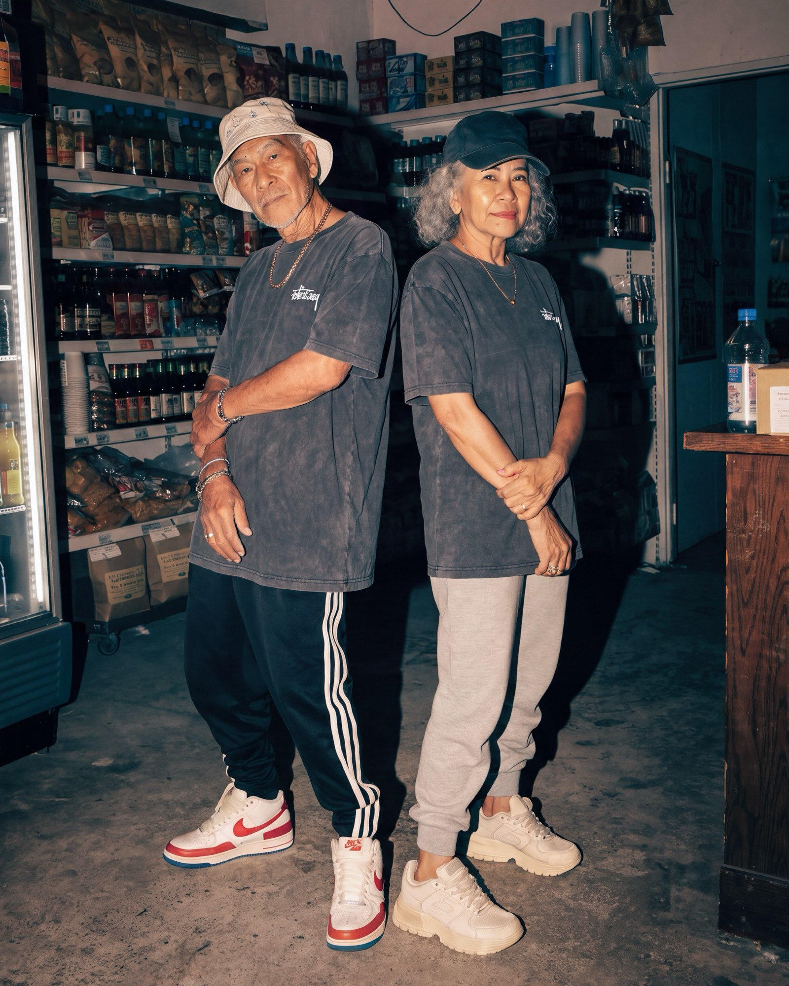 Two people wearing the charcoal Take It Easy tee, standing together in a corner store