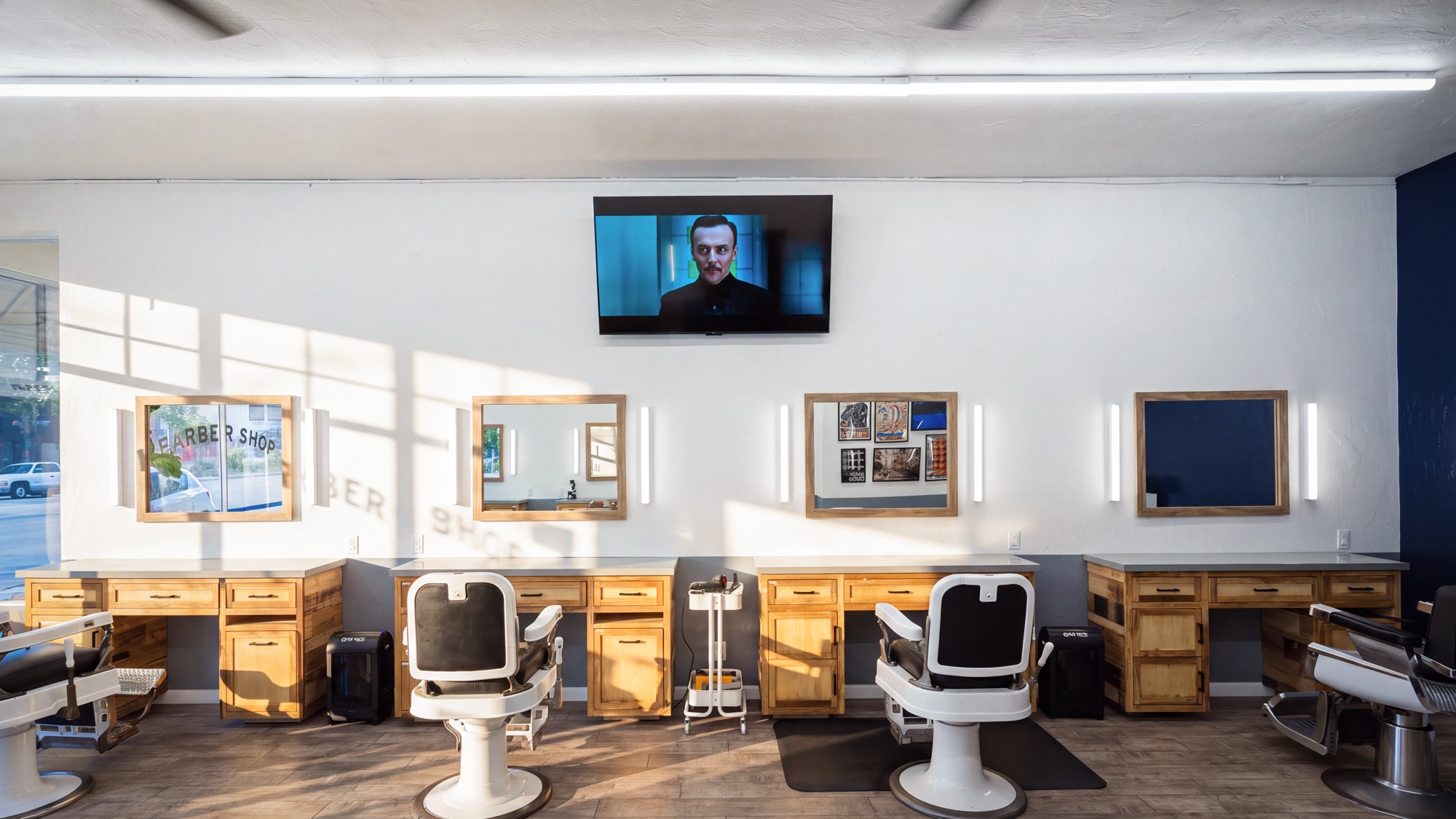 The shared room at Juan’s Barbershop — a row of stations, mirrors and chairs along one wall